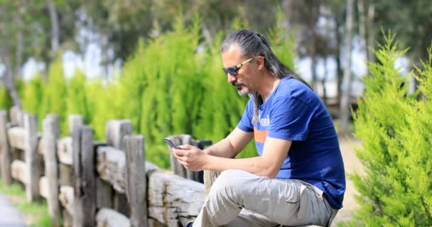 Homem com celular na natureza verde — Vídeo de Stock