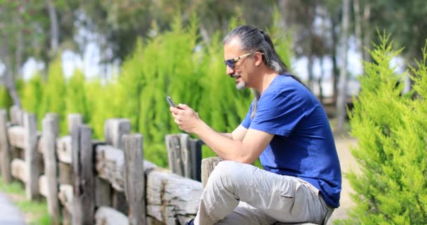 Man met mobiele telefoon in de groene natuur — Stockvideo