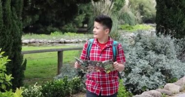 Yeşil doğada yürüyen haritalı genç mutlu gezgin.