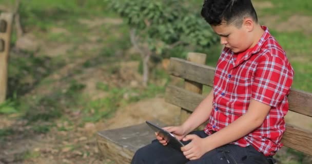 Retrato de un adolescente caucásico con tableta digital en la naturaleza — Vídeos de Stock