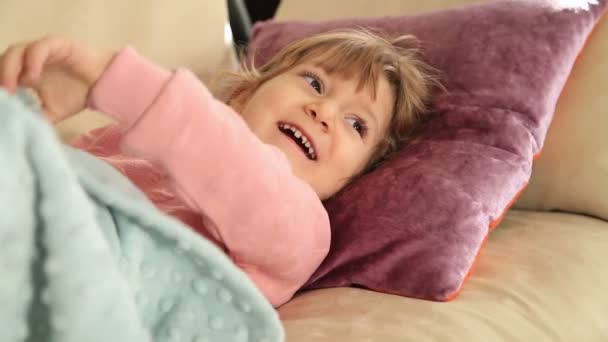 Милая маленькая девочка отдыхает на диване — стоковое видео