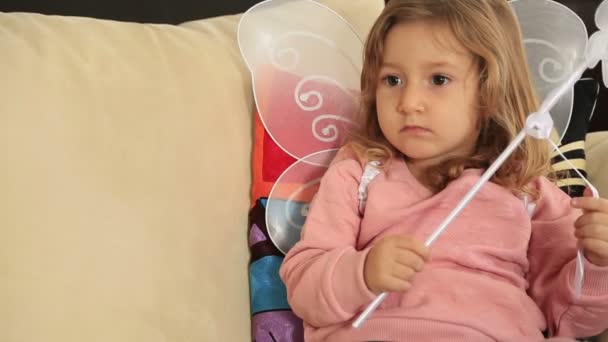 Портрет милой маленькой девочки с ангельским крылом, смотрящей телевизор — стоковое видео