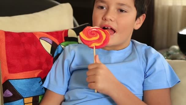 Niño lindo joven con caramelos de piruleta de colores grandes — Vídeos de Stock