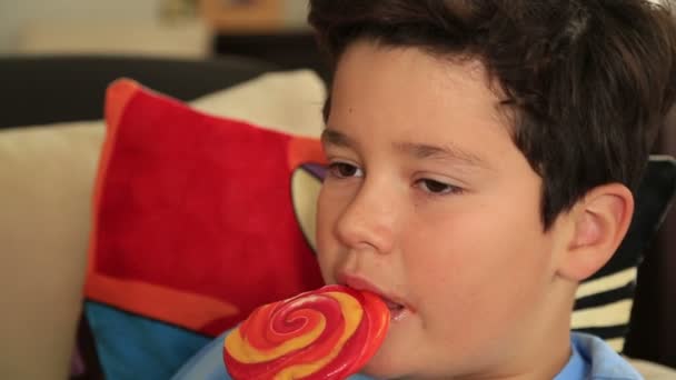 Fiatal aranyos fiú, a nagy színes nyalóka candy — Stock videók