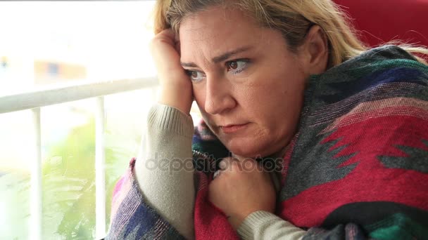 Sad young woman looking through window — Stock Video