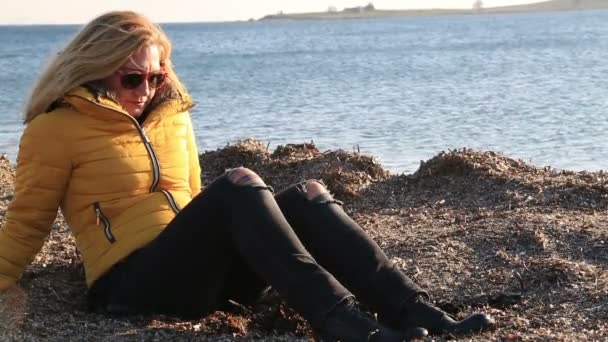 Vrouw in warme kleding, zittend op winter strand — Stockvideo