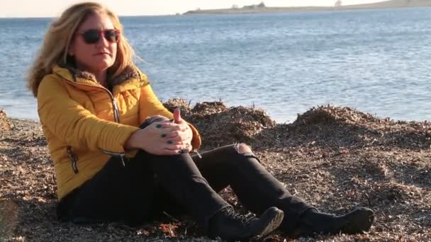 Γυναίκα στις διακοπές που κάθεται στην παραλία του χειμώνα — Αρχείο Βίντεο