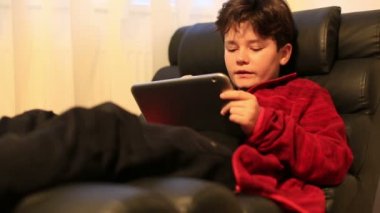 Kanepede yatan ve dijital tablet bilgisayar kullanarak çocuk çocuk