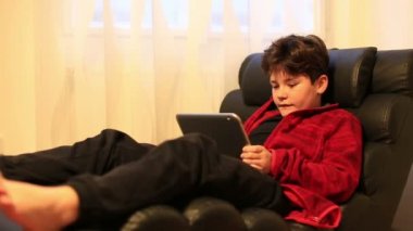 Kanepede yatan ve dijital tablet bilgisayar kullanarak çocuk çocuk