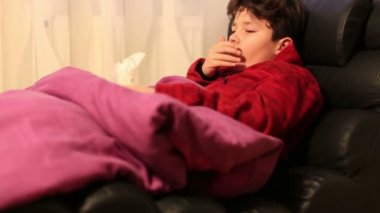 Yorgun, zayıf çocuk evde yatakta yatarken ve dinlenme grip hasta. Burnunu bir kağıt mendil darbeler