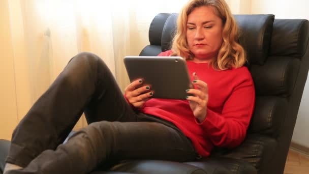 Ξανθιά γυναίκα στον καναπέ χρησιμοποιώντας ψηφιακό tablet — Αρχείο Βίντεο