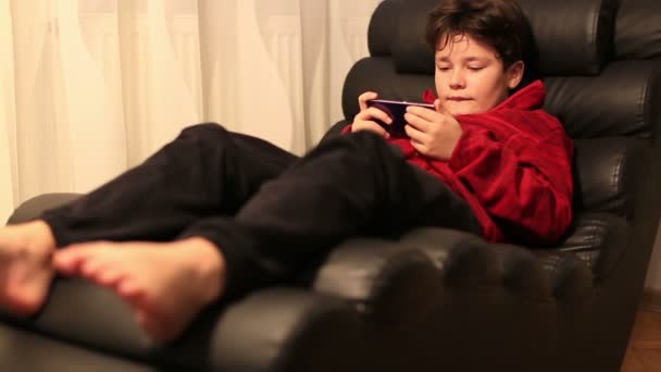 Schoolboy lying and gaming on the smartphone at home — Stock Video