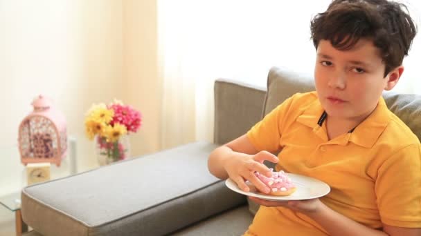 Mladý chlapec jíst koblihy — Stock video