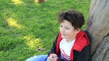 Yeşil çimenlerin üzerinde oturan bir gülümseyen çocuk portresi