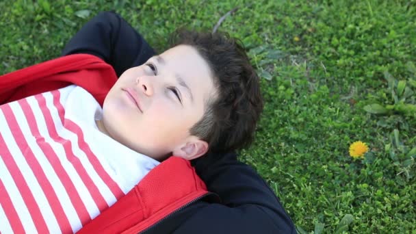 Gyermek zöld füvön fekszik, és pihennek — Stock videók