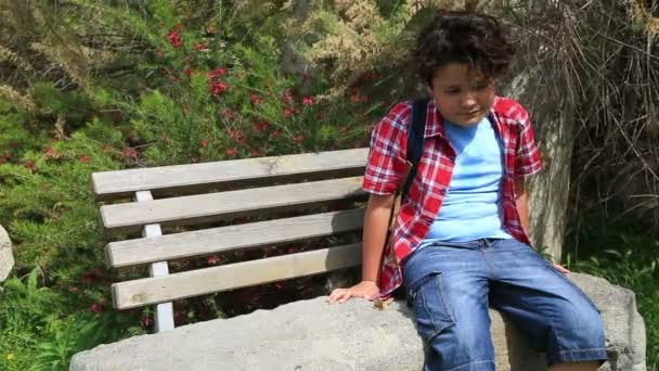 Child sitting on a park bench — Stock Video