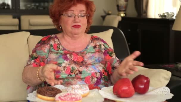 お菓子と果物 4 の間を選択する女性 — ストック動画