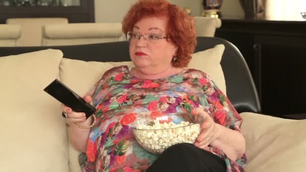 Nainen katsomassa televisiota, syömässä popcornia — kuvapankkivideo
