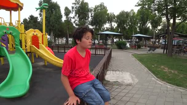 Грустный мальчик на детской площадке — стоковое видео