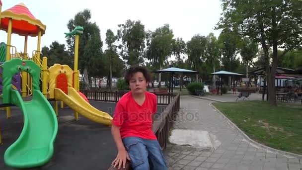 Niño triste en el patio de recreo — Vídeo de stock