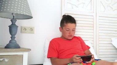 Bir yatakta yatarken ve akıllı telefon kullanarak çocuk. Smartphone bağımlılığı