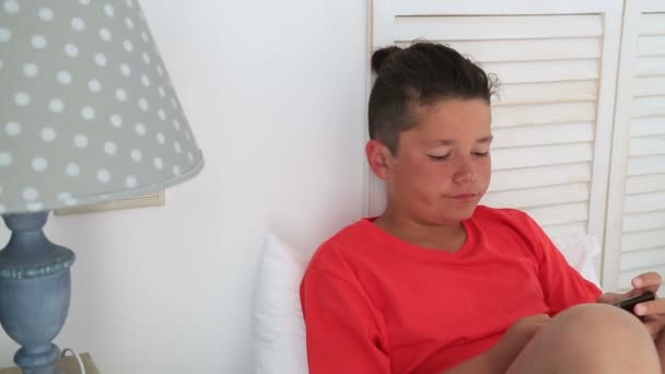 Молодий хлопчик грає з мобільним смартфоном — стокове відео