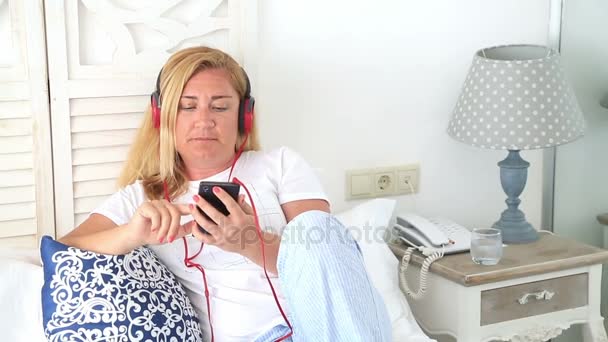 Kadın bir yatak 3 döşeme kulaklık ile — Stok video