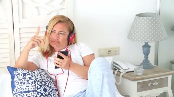 Mujer con auriculares acostada en una cama 5 — Vídeos de Stock