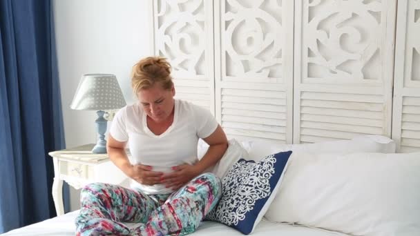 Femme souffrant de douleurs abdominales couchée sur un lit — Video