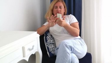 Uzaktan kumanda 2 düğmesine basan mutsuz kadın