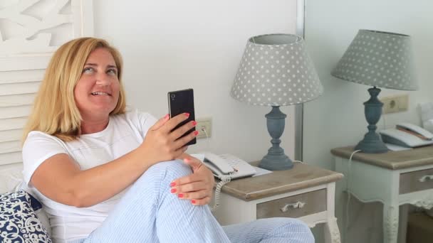 一名中年有魅力的女人 阅读和写作的智能手机在床上 — 图库视频影像