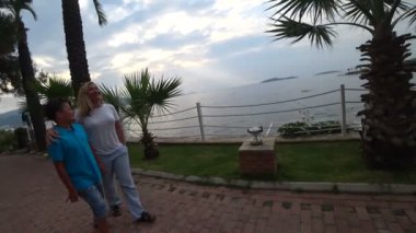 Anne ve oğlu deniz kıyısında günbatımı yürüyerek.