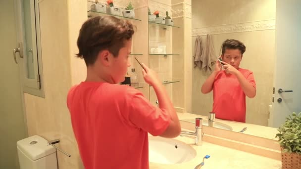 Porträt eines hübschen Jungen, der sich die Haare bürstet — Stockvideo