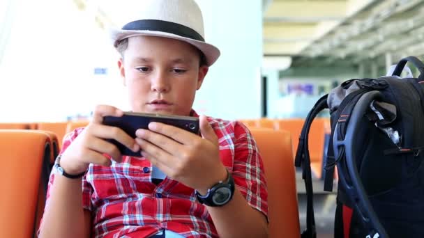 Niño con teléfono inteligente en el aeropuerto — Vídeos de Stock