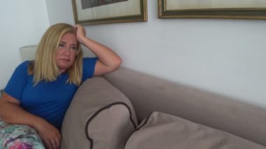 Üzgün kadın kanepede oturuyor.