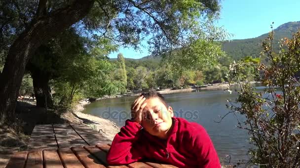 Mignon preteen garçon assis sur un banc et rêvasser 2 — Video