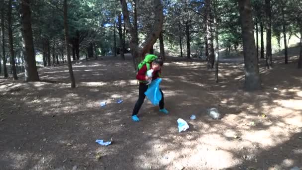 Young boy picking up trash in nature — Stock Video