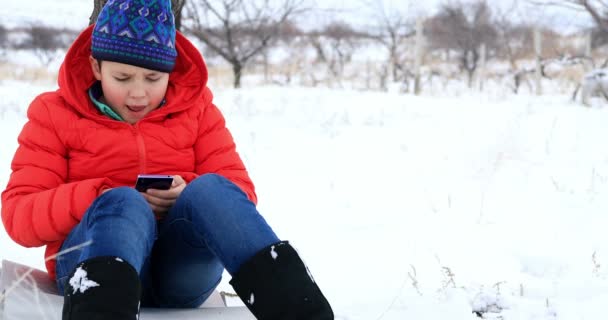 Niño usando smartphone en el parque de invierno 3 — Vídeos de Stock