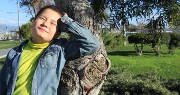 Młody chłopak relaksujący pod światłem słonecznym w parku — Wideo stockowe