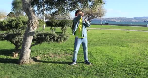 Niño con auriculares bailando en el césped 2 — Vídeos de Stock