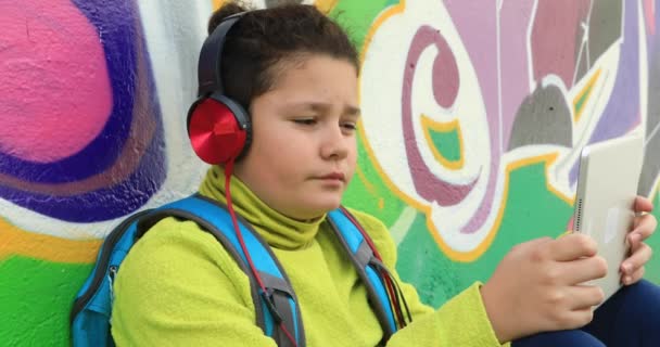 Молодий хлопець з навушниками за допомогою цифрового планшета 2 — стокове відео