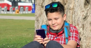 Smartphone teknolojisi, Internet iletişim ve insan kavramı, Smartphone bağımlılığı söz yeşil bahar parkta oturan bir mutlu varoluş çocuk portresi