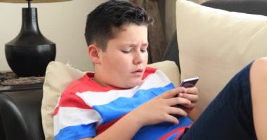 Kanepede oturan ve evde smartphone kullanarak mutlu bir varoluş çocuk portresi. Teknoloji, Internet iletişim ve insan kavramı, Smartphone bağımlılığı