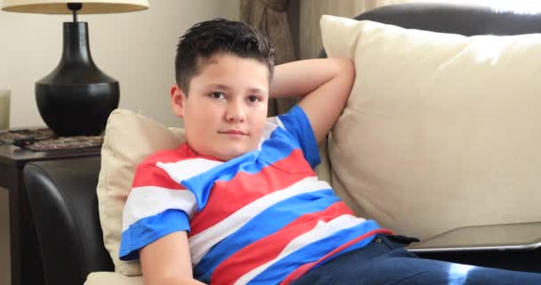 一个轻松的青春期男孩的肖像躺在沙发上 遥控器和在家看电影的内部 — 图库视频影像