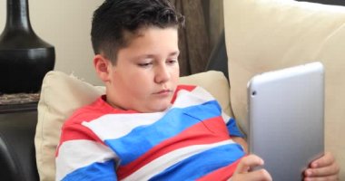 Portre rahat, genç bir çocuğun ev iç adlı çizgi film izlerken dijital tablet ile kanepede döşenmesi
