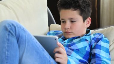 Dijital tablet manifatura iletisiyle koltuk döşeme veya evde oyun oynarken rahat bir varoluş çocuk portresi. Teknoloji, Internet iletişim ve insan kavramı