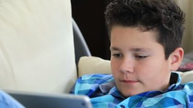 Dijital tablet manifatura iletisiyle koltuk döşeme veya evde oyun oynarken rahat bir varoluş çocuk portresi. Teknoloji, Internet iletişim ve insan kavramı