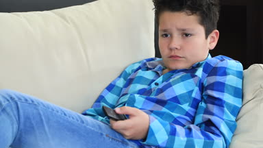 Evde televizyon izlerken koltukta yalan uzaktan kumanda ile genç bir varoluş çocuk portresi