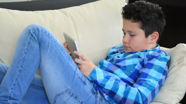 一个轻松的青春期男孩的肖像铺设沙发与数字平板电脑短信或在家里玩游戏 网络传播与人的概念 — 图库视频影像