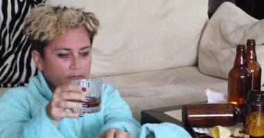 Depresyondaki sefil kadın, yerde tek başına oturuyor ve alkol içiyor.
